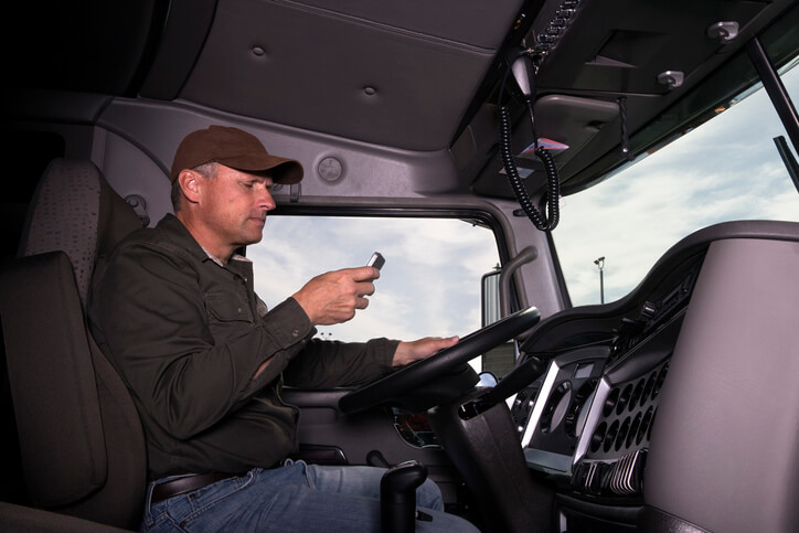 A driver looks at his cellphone as he sits in a fleet vehicle.