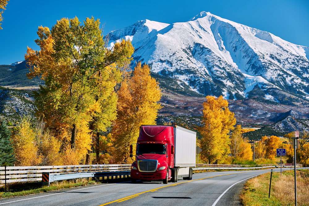 Truck driving on a highway with mountains in the background