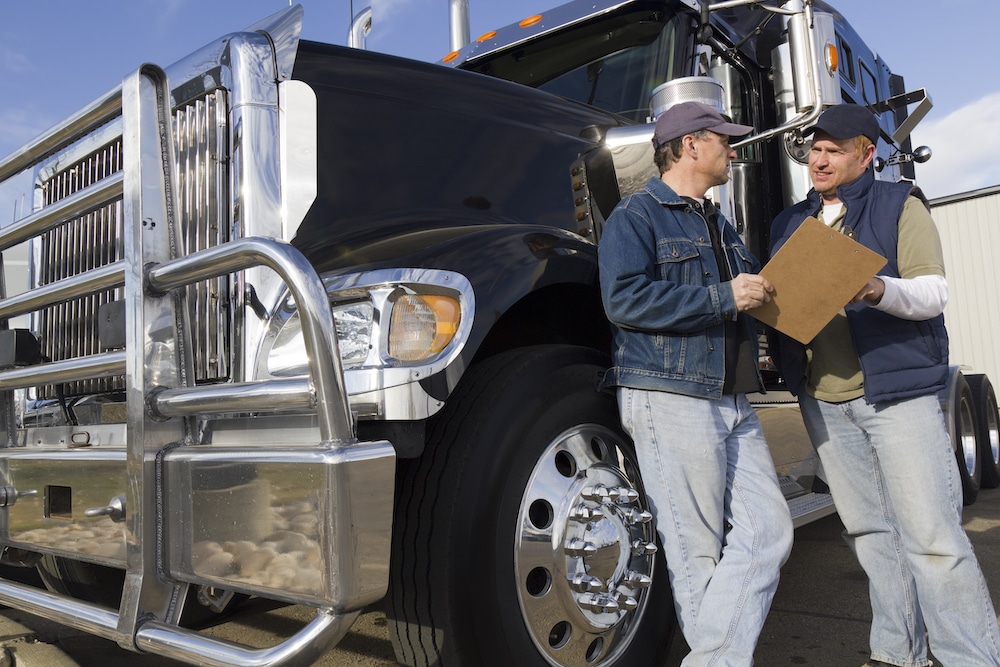 Two fleet workers talking in front of a semi truck