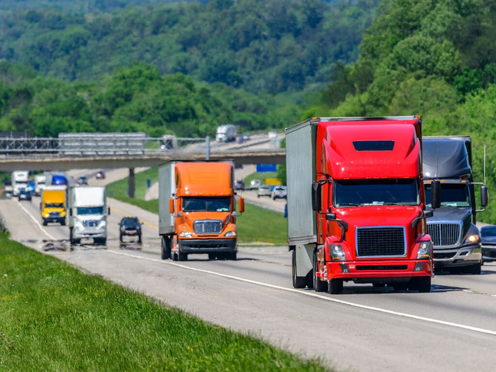 A steady flow of semi trucks equipped with AI-enabled dash cams  on a busy interstate highway